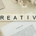 Kafelkowe litery układające się w napis Creative na notesie w linię