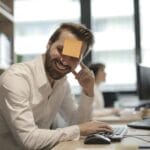 Mężczyzna w nowoczesnym biurze z karteczką samoprzylepną na czole