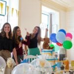 Trzy uśmiechnięte kobiety świętują w domu wśród balonów i dekoracji