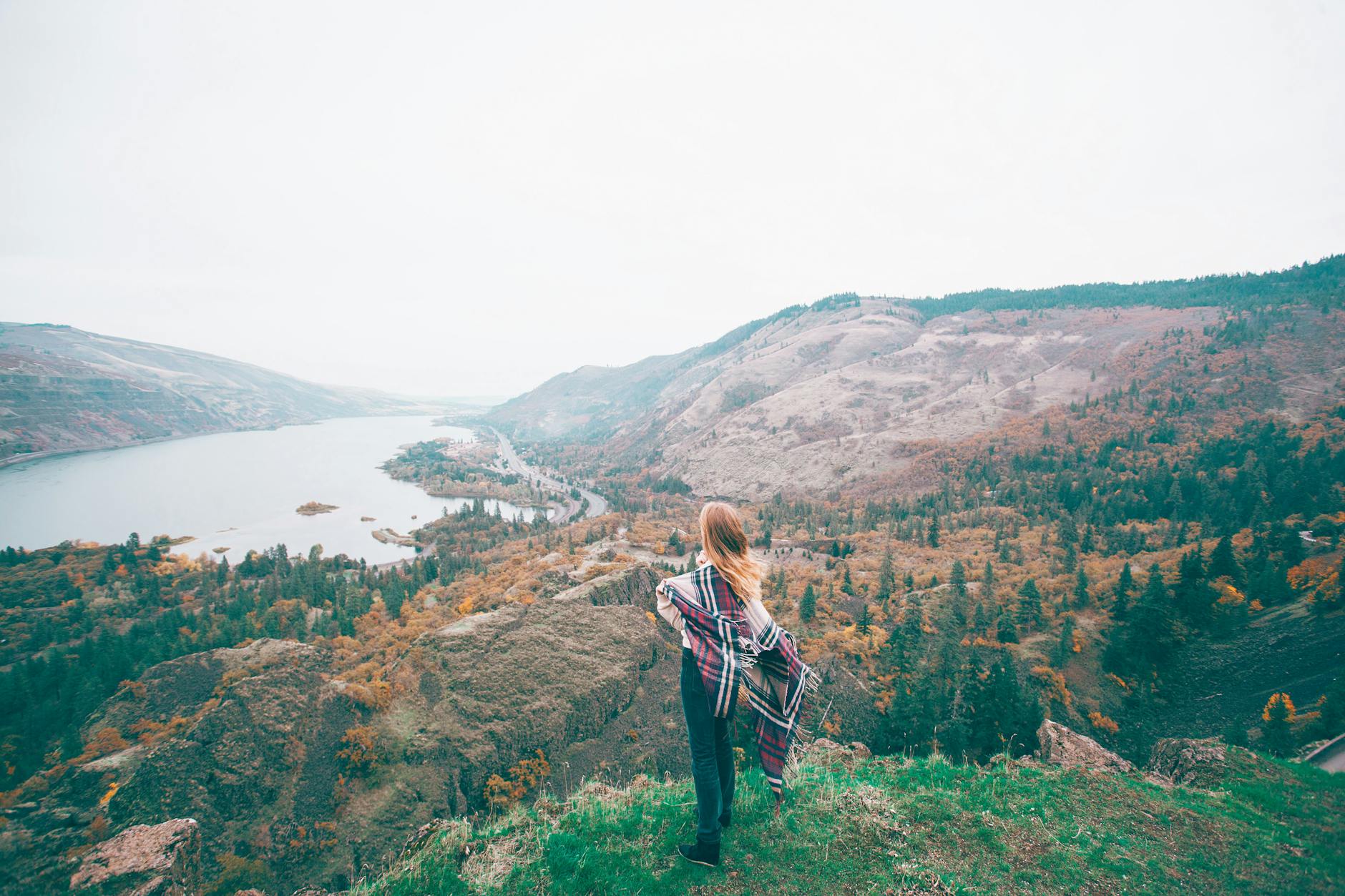 Turystka w kolorowej chuście podziwia jesienną rzekę w górskiej dolinie