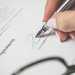 Dłoń podpisująca umowę licencyjną na muzykę eleganckim piórem