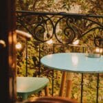 Mały balkon w angielskim stylu z niebieskim stolikiem, krzesłem i lampkami