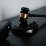Młotek sędziowski na biurku obok segregatorów z dokumentami
