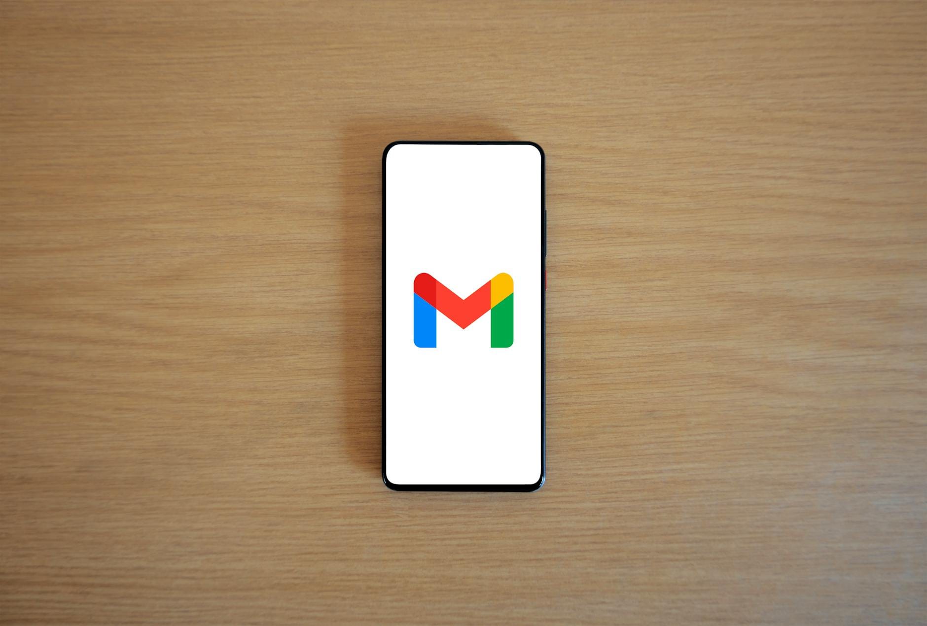 Smartfon z logo Gmail leżący na drewnianym blacie