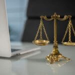 Złota waga sprawiedliwości na biurku obok otwartego laptopa