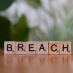 Drewniane kostki z napisem Breach na tle rozmytego naturalnego otoczenia