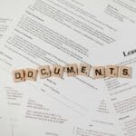 Kafelki scrabble z napisem DOCUMENTS leżące na stosie umów i regulaminów