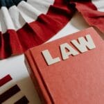 Książka z napisem LAW obok czerwono-biało-czarnej wstążki