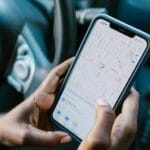 Smartfon z nawigacją GPS trzymany w rękach kierowcy w samochodzie