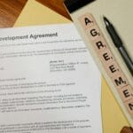 Umowa licencyjna na biurku z długopisem i kostkami z napisem AGREEMENT