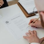 Zbliżenie na rękę podpisującą dokument rozwodowy na biurku