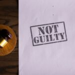 Dokument z napisem Not Guilty i sędziowski młotek na biurku