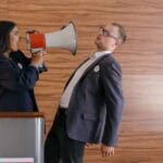 Dwóch polityków w gorącej kłótni, jeden krzyczy przez megafon