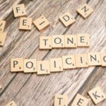 Kafle scrabble układające się w napis Tone Policing na drewnianym blacie