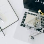 Miniaturowy wózek sklepowy stojący na klawiaturze laptopa